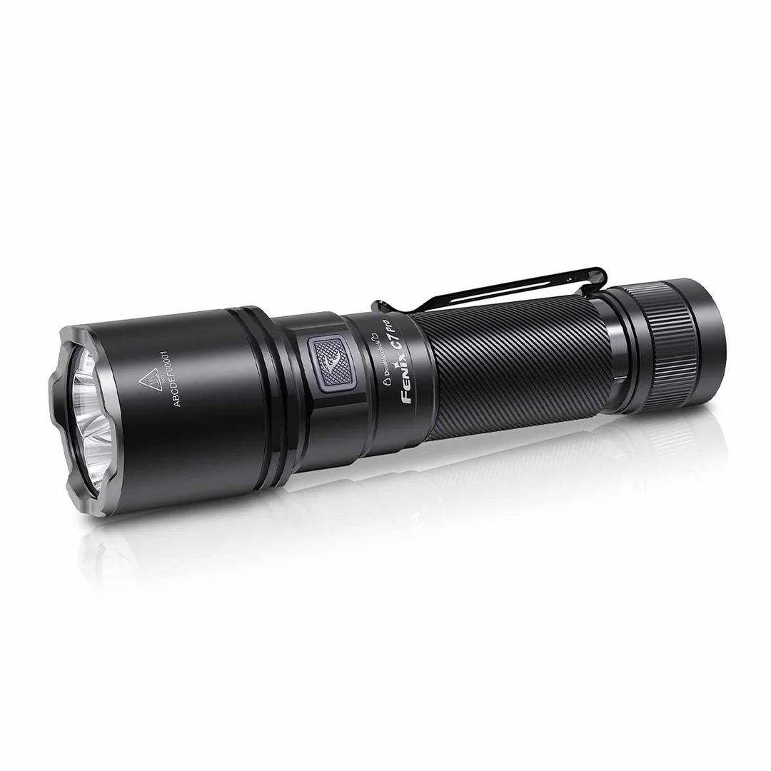 Black tactical flashlight with textured grip and metal clip, lying on a white reflective surface.