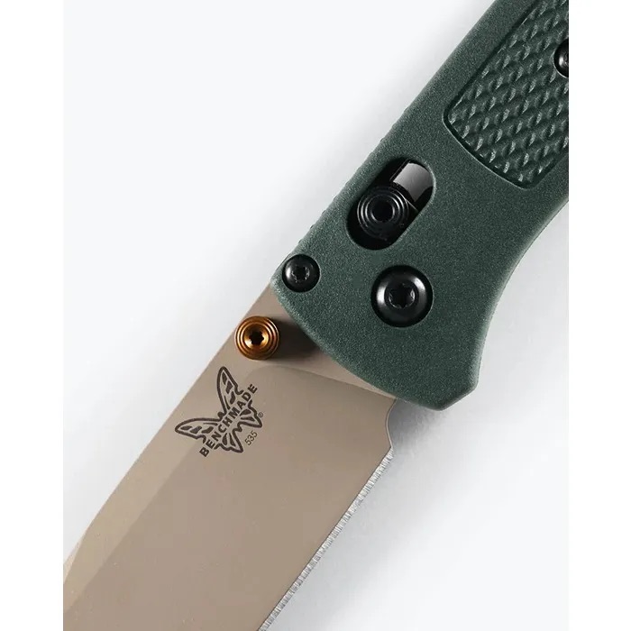 Close-up of a green-handled folding knife blade, showing the Benchmade logo and a bronze pivot insert near the blade