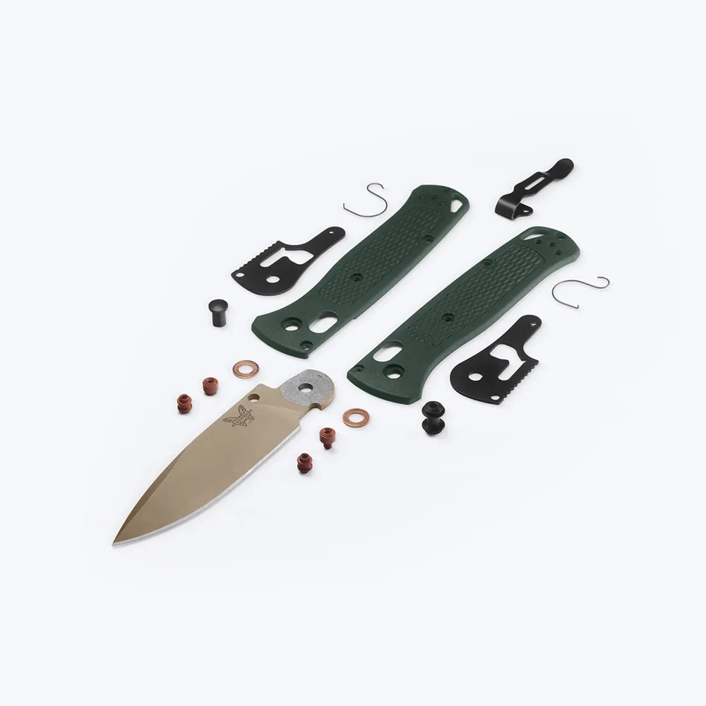 Disassembled knife kit with a blade, green handle scales, screws, washers, and spacers laid out on a white background (repair parts).