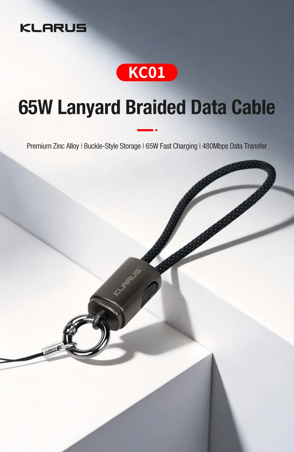 Klarus KC01 65W braided data cable with a black lanyard and metal ring, shown on a white geometric surface.