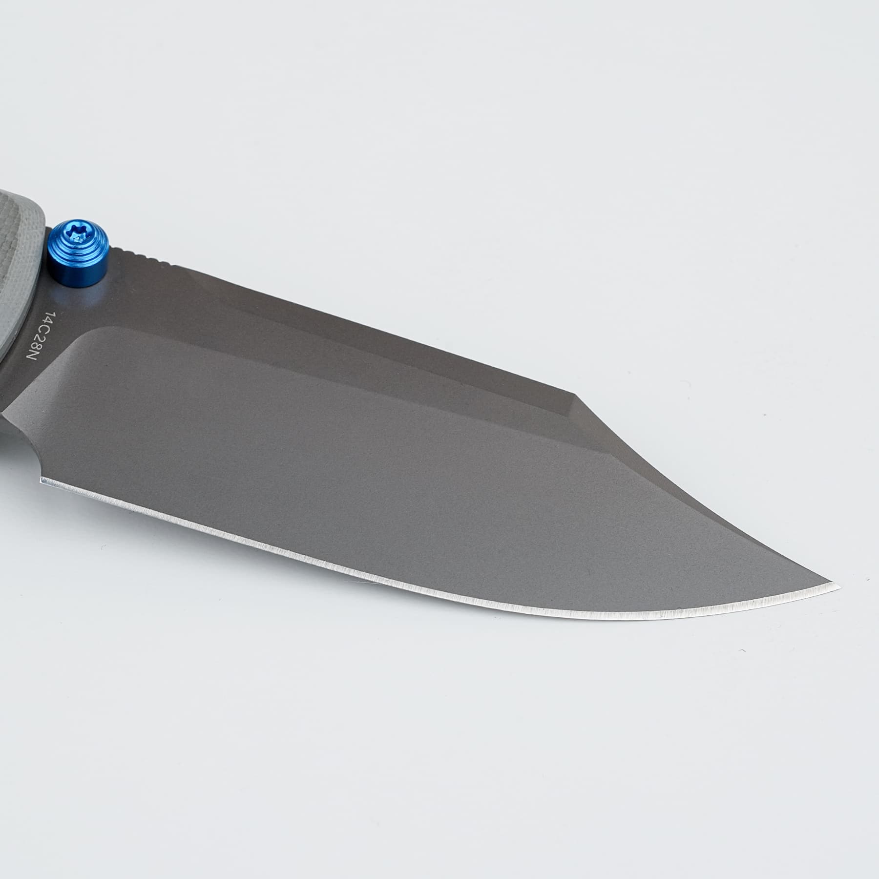 Close-up of a gray knife blade with a small blue anodized screw at the handle against a white background.