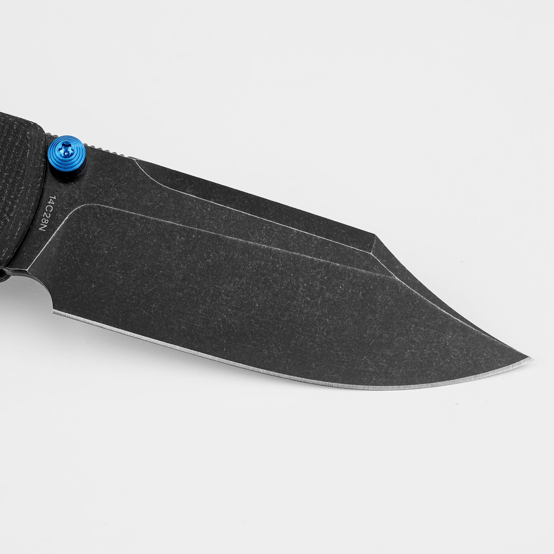 Close-up of a black folding knife blade with a bright blue screw near the handle against a white background.