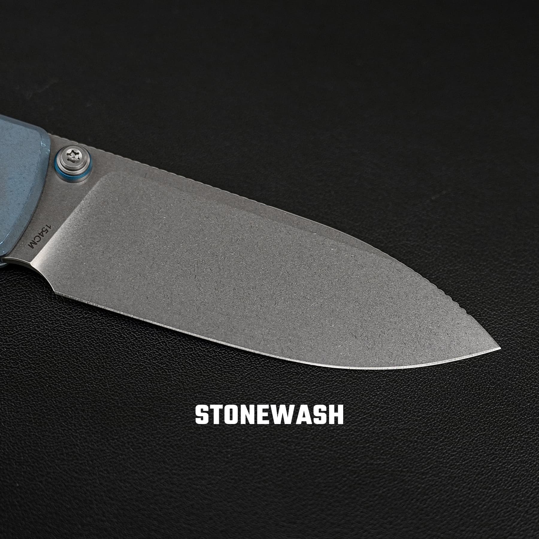 Close-up of a stonewashed knife blade with a blue pivot screw against a black textured background, and 'STONEWASH' text visible at the bottom.