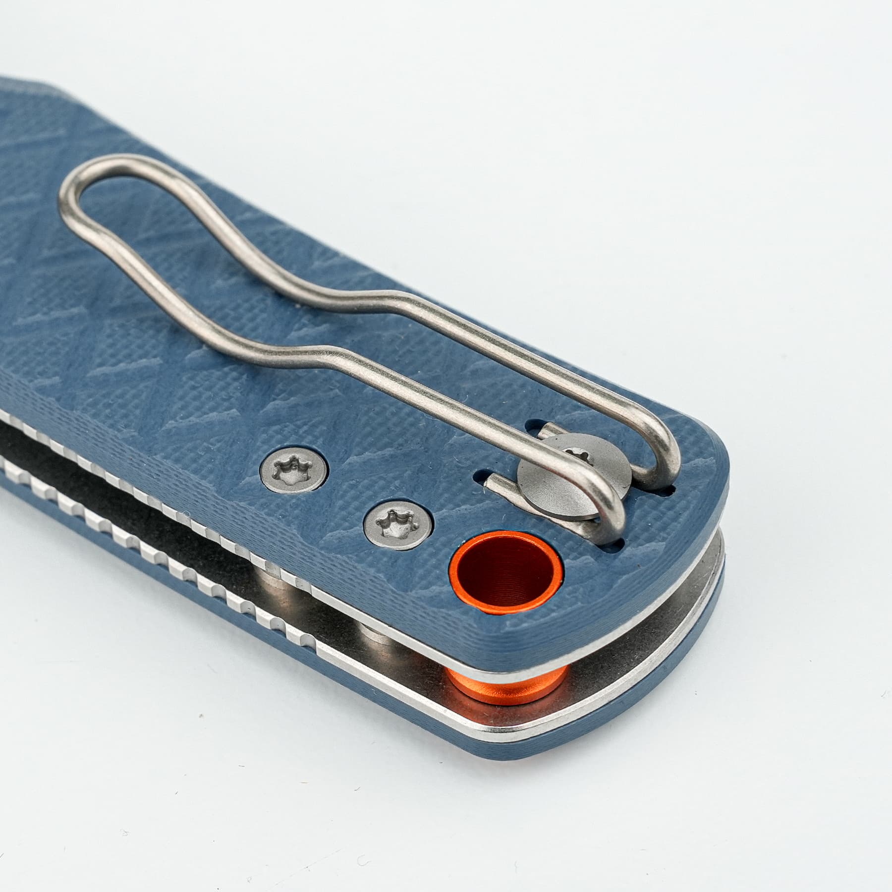 Close-up of a blue textured device with a curved metal wire spring and an orange circular opening at the edge.