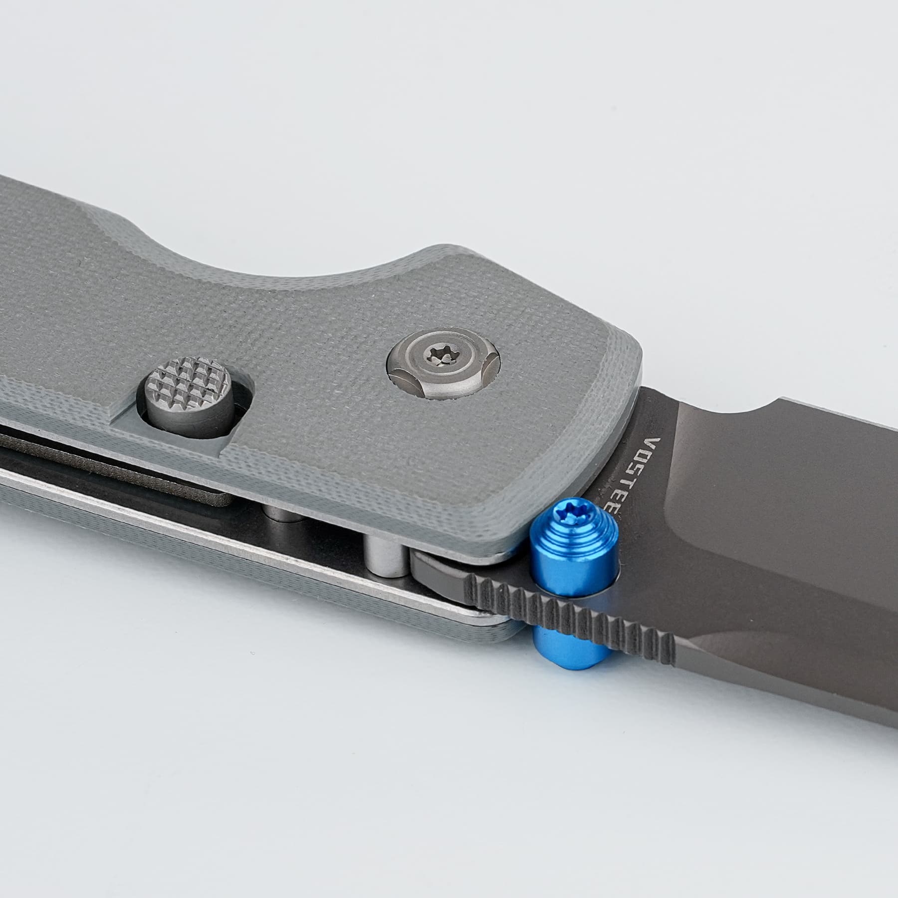 Close-up of a gray metal clamp with a knurled adjustment knob and a blue fastener, part of a precision tool or jig