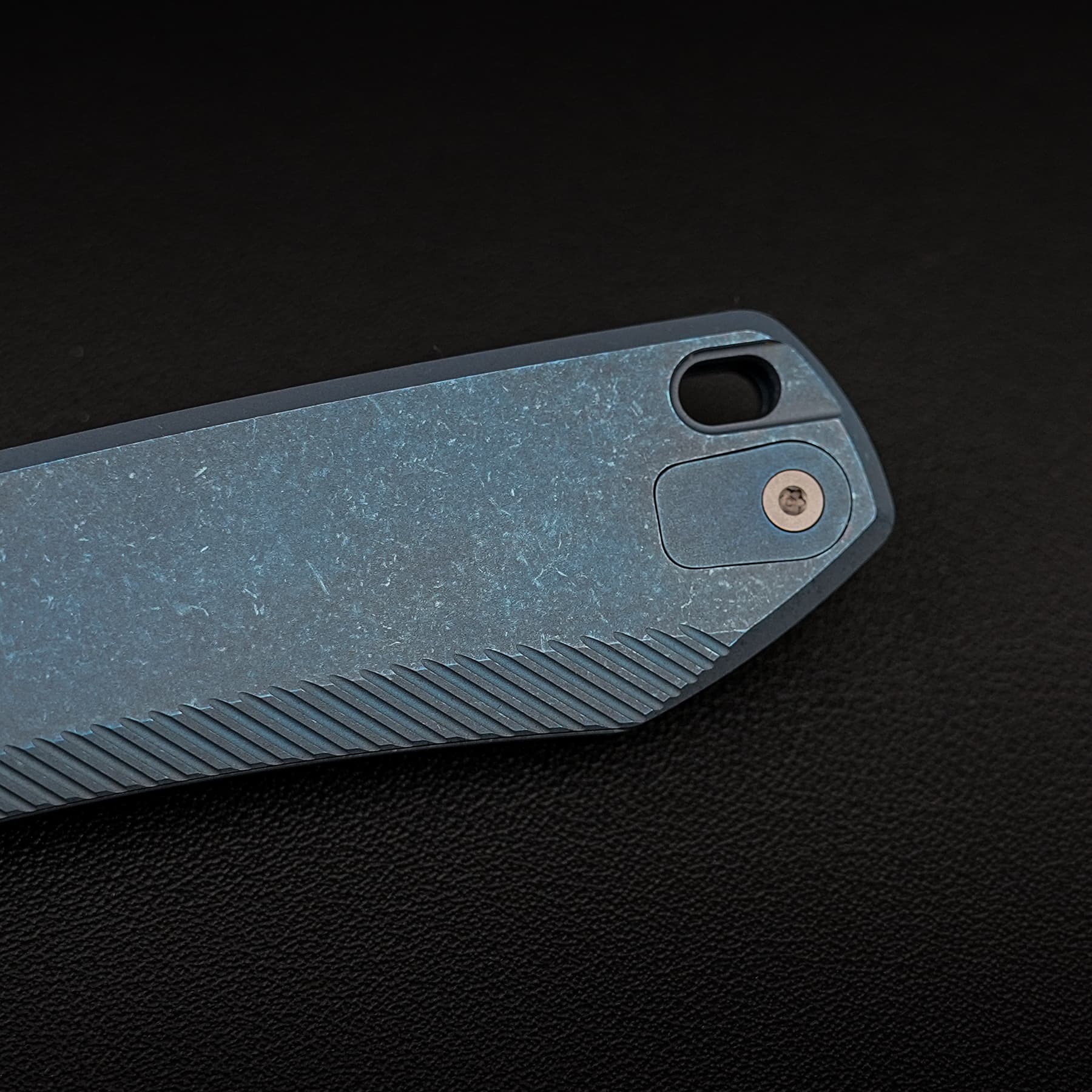 Close-up of a weathered blue-gray pocketknife handle with a textured grip and visible screws against a dark background.