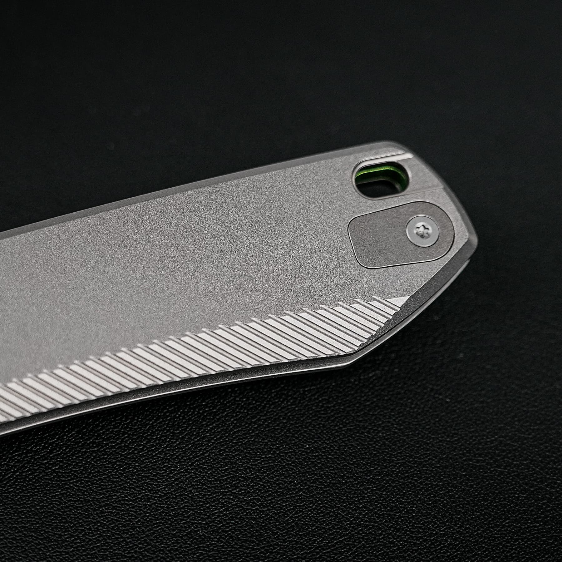 Close-up of a silver device edge with a rounded port showing a green interior on a black background.