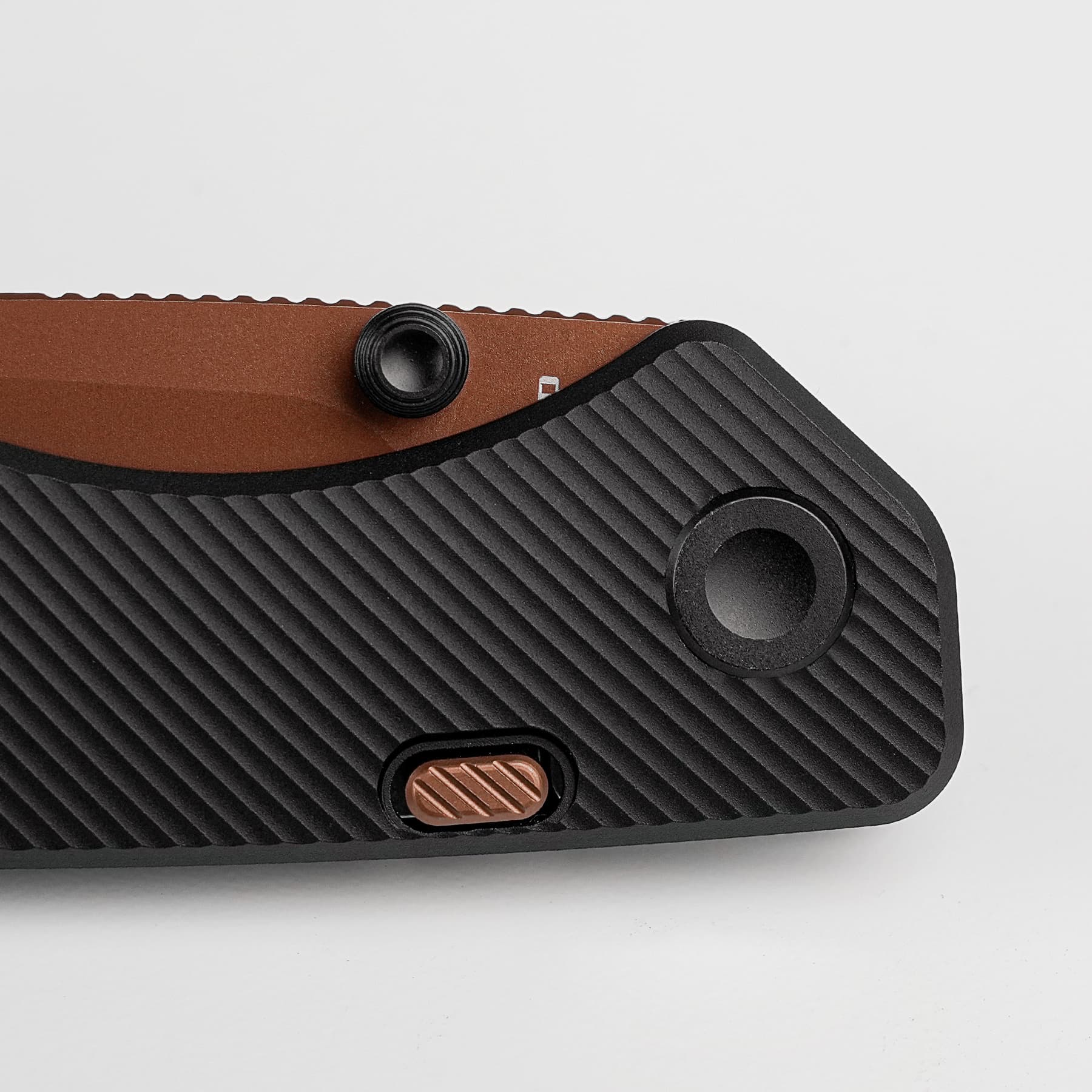 Close-up of a textured black surface with a brown strip and an orange ribbed slider/button, along with a small black circular knob.