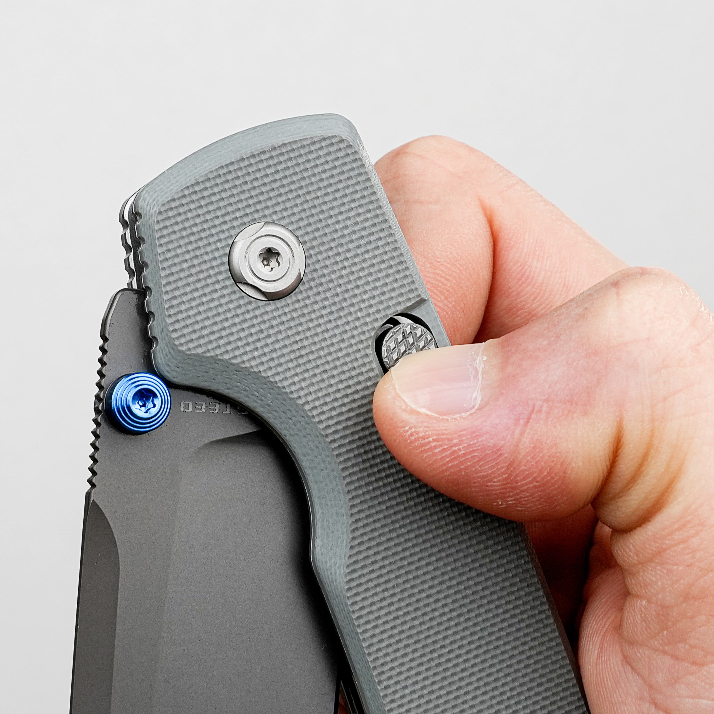 Close-up of a hand using a gray folding utility knife, engaging the blade lock.