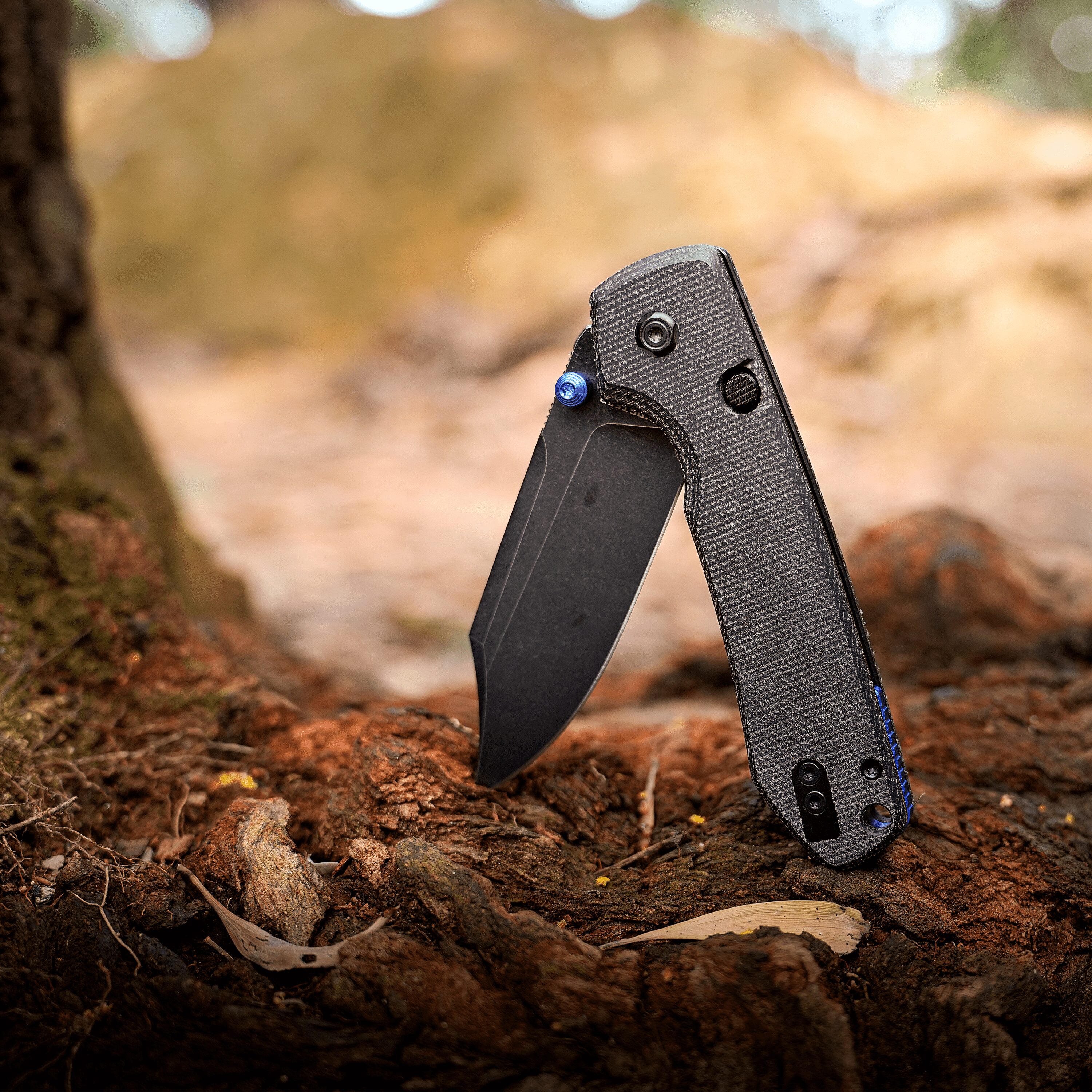 Close-up of a black carbon bike fork with a blue bolt on a dirt forest trail.