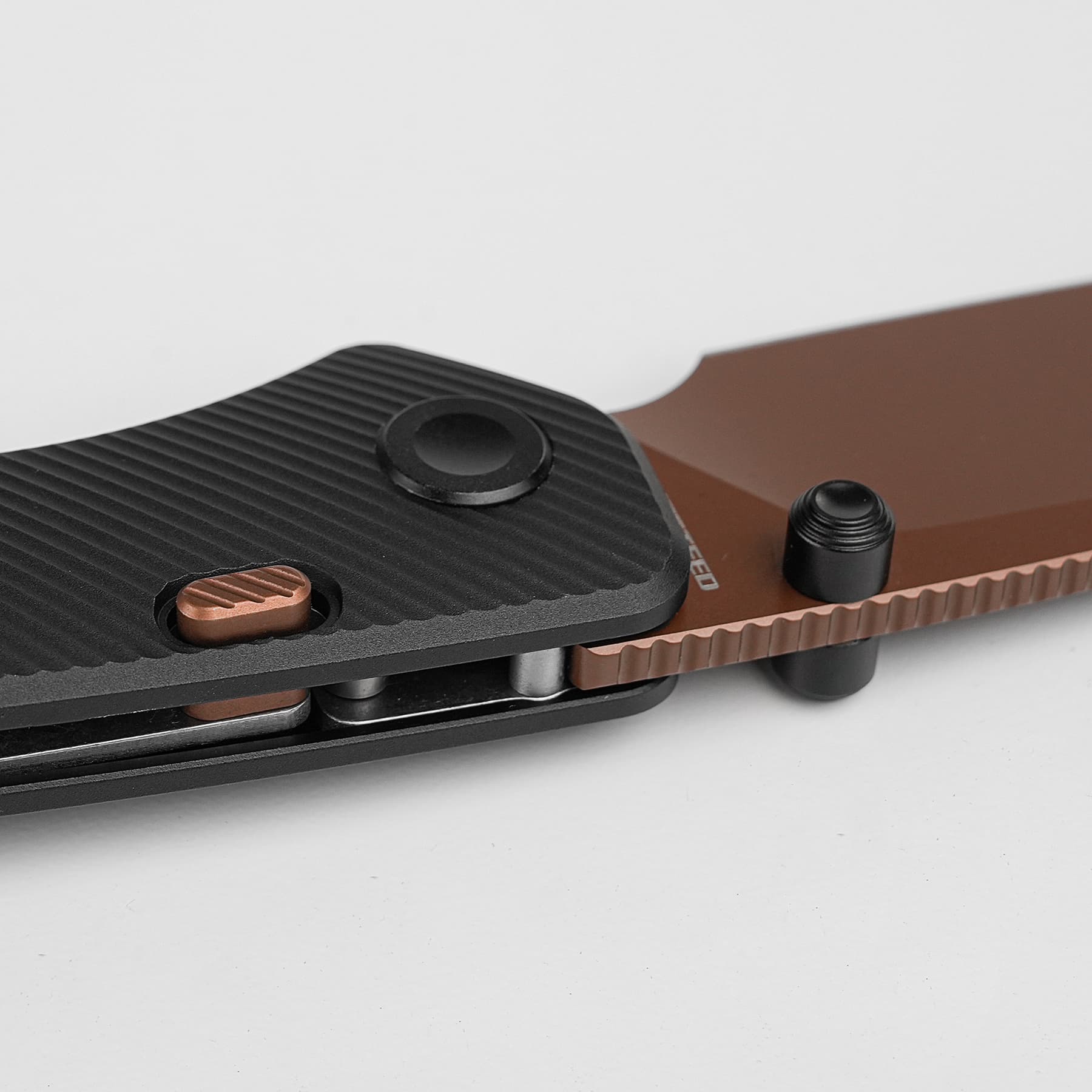 Macro shot of a textured black surface with a circular black knob and copper metal piece on a brown base.