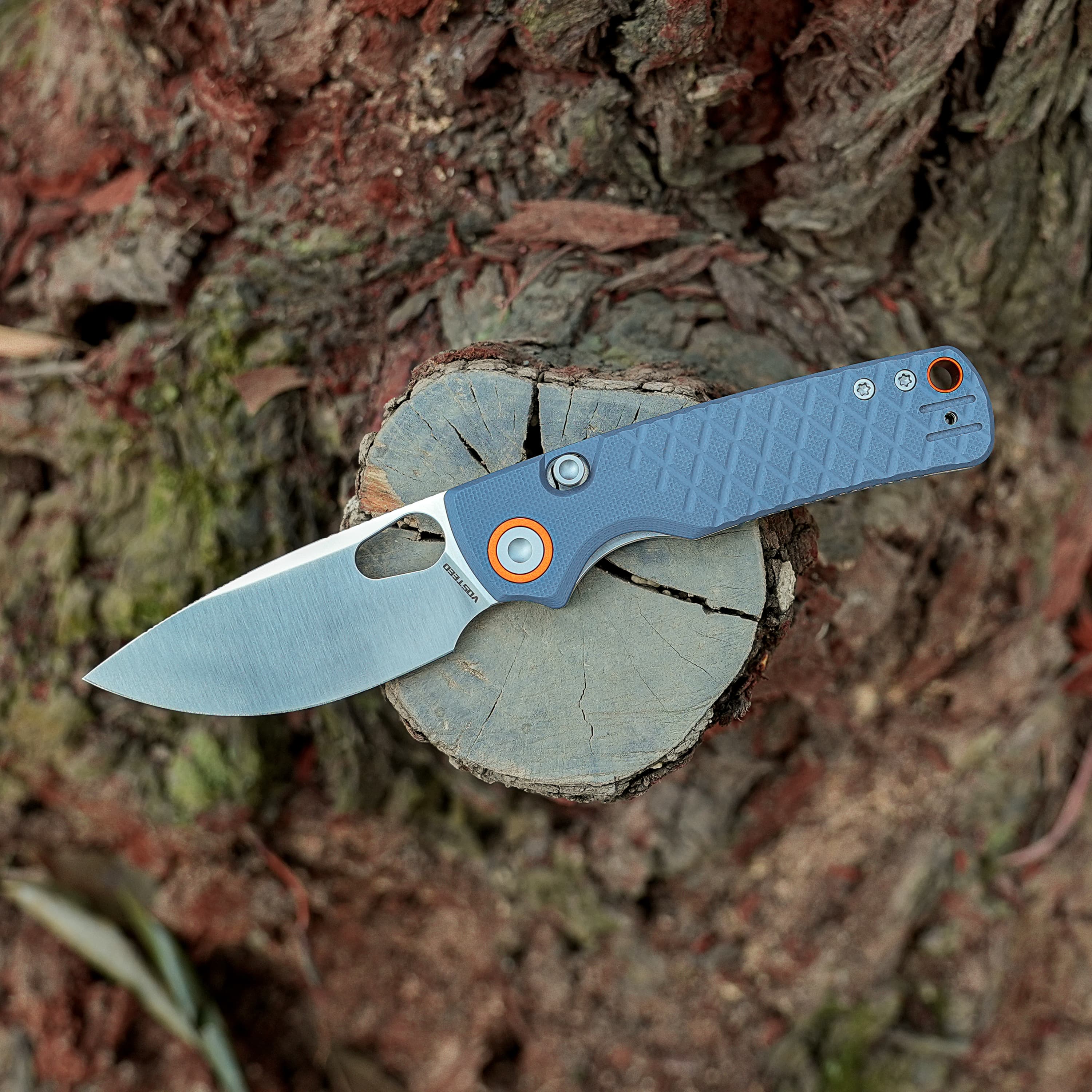 Blue-handled cutting tool resting on a freshly cut tree stump, orange screws visible on the handle area.