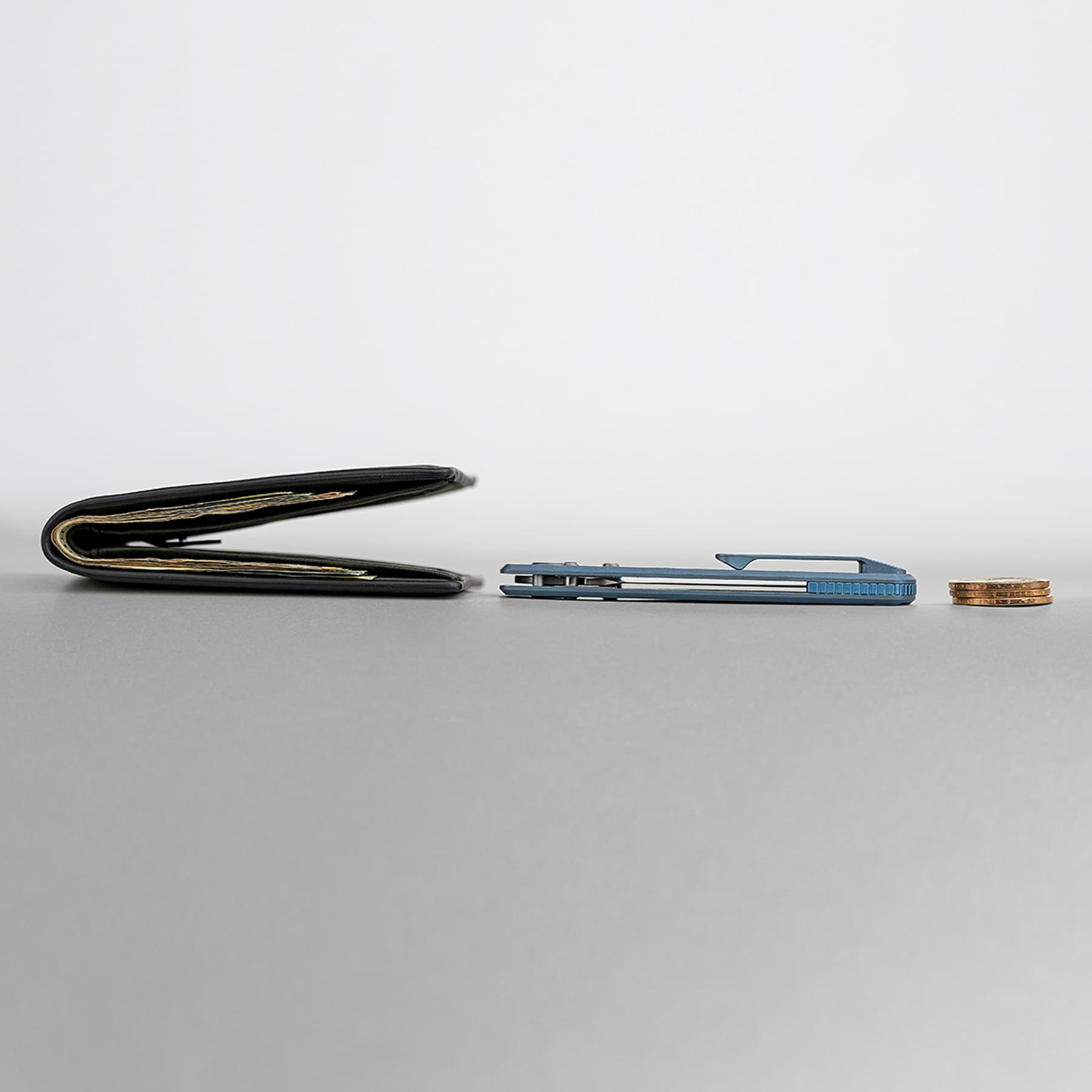 Open black wallet with cards visible on a gray desk, beside a blue stapler and a small stack of coins.