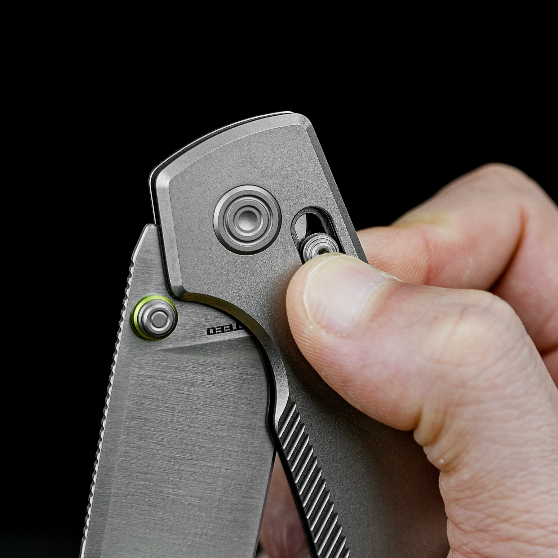 Close-up of a hand holding a silver folding utility knife, with the blade partially exposed and a safety lock near the top, against a black background.