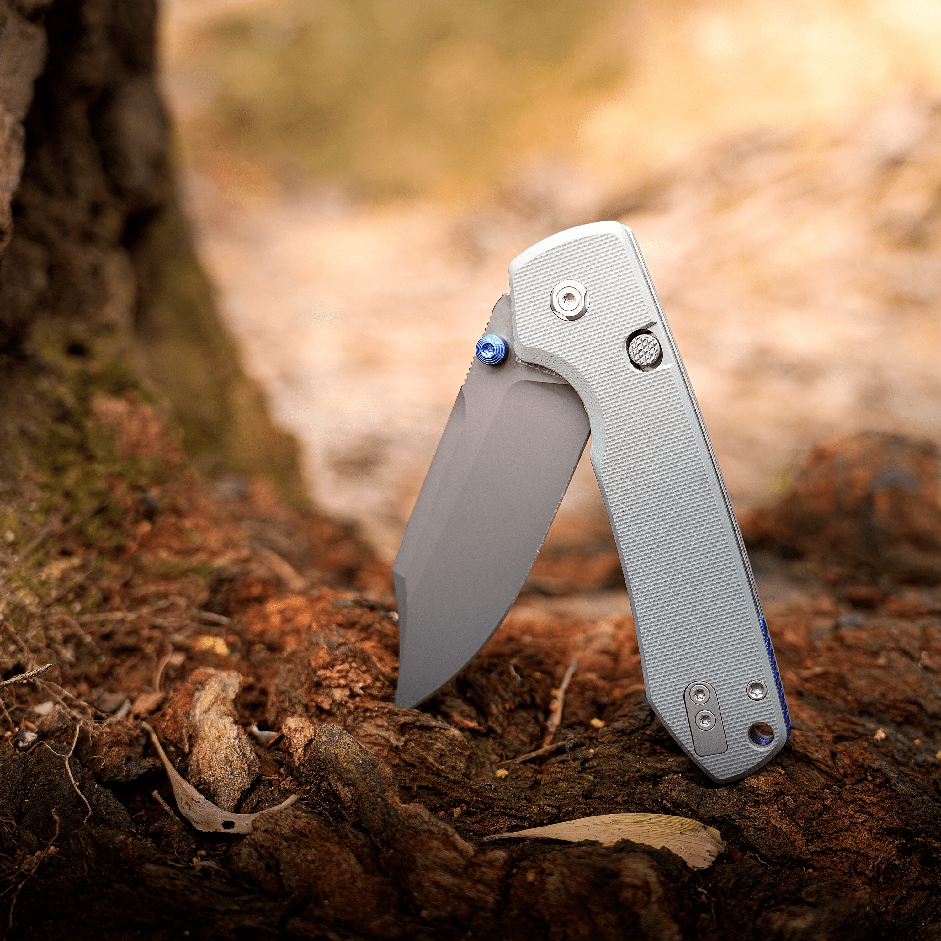Close-up of a folding utility knife blade exposed on dirt ground outdoors.