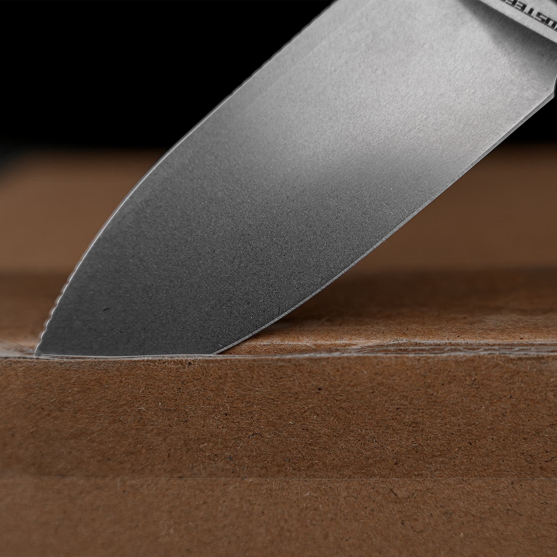 Close-up of a metal kitchen knife blade resting on a wooden cutting board, angled diagonally across the frame