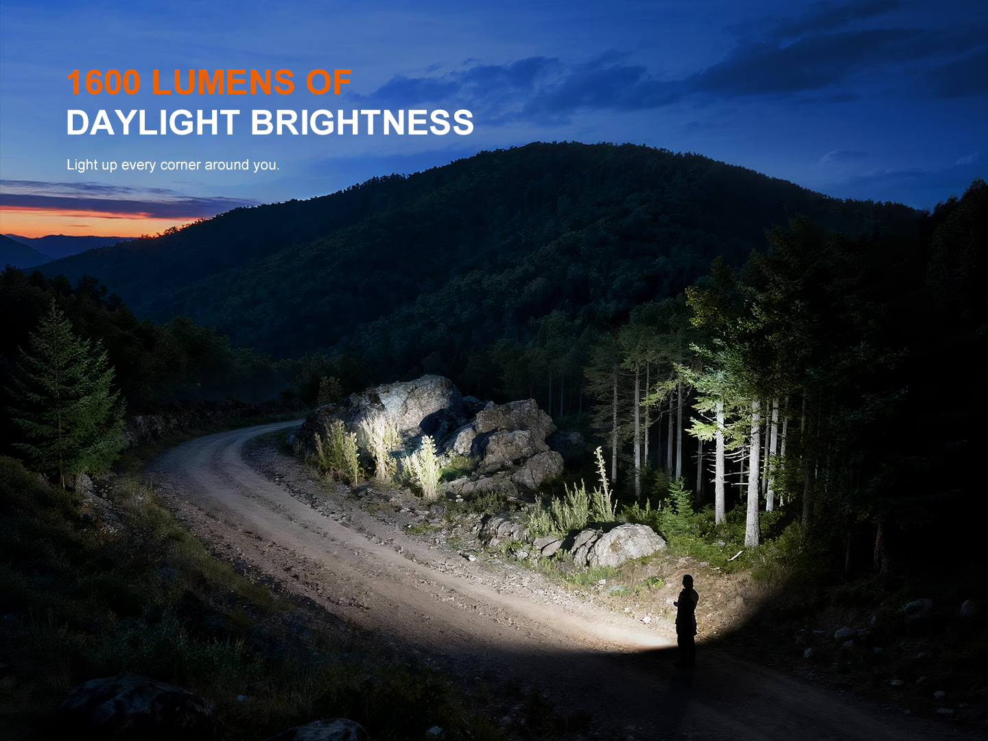 Hiker on a dirt road at dusk, a bright flashlight beam illuminating rocks and trees in a forested mountain landscape.