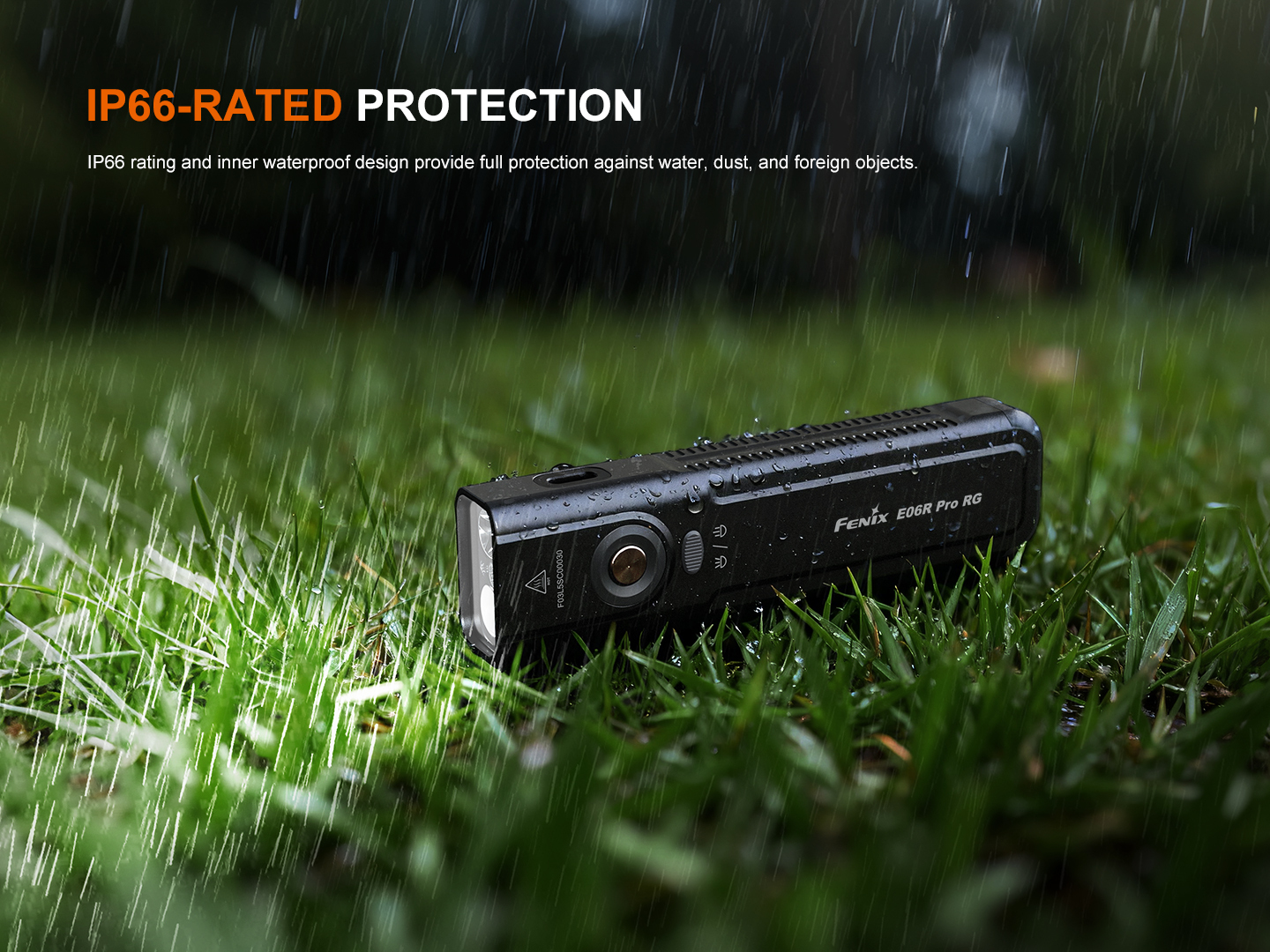 Black Fenix E60R Pro RG flashlight lying on wet grass in rain, highlighting IP66 waterproof protection.