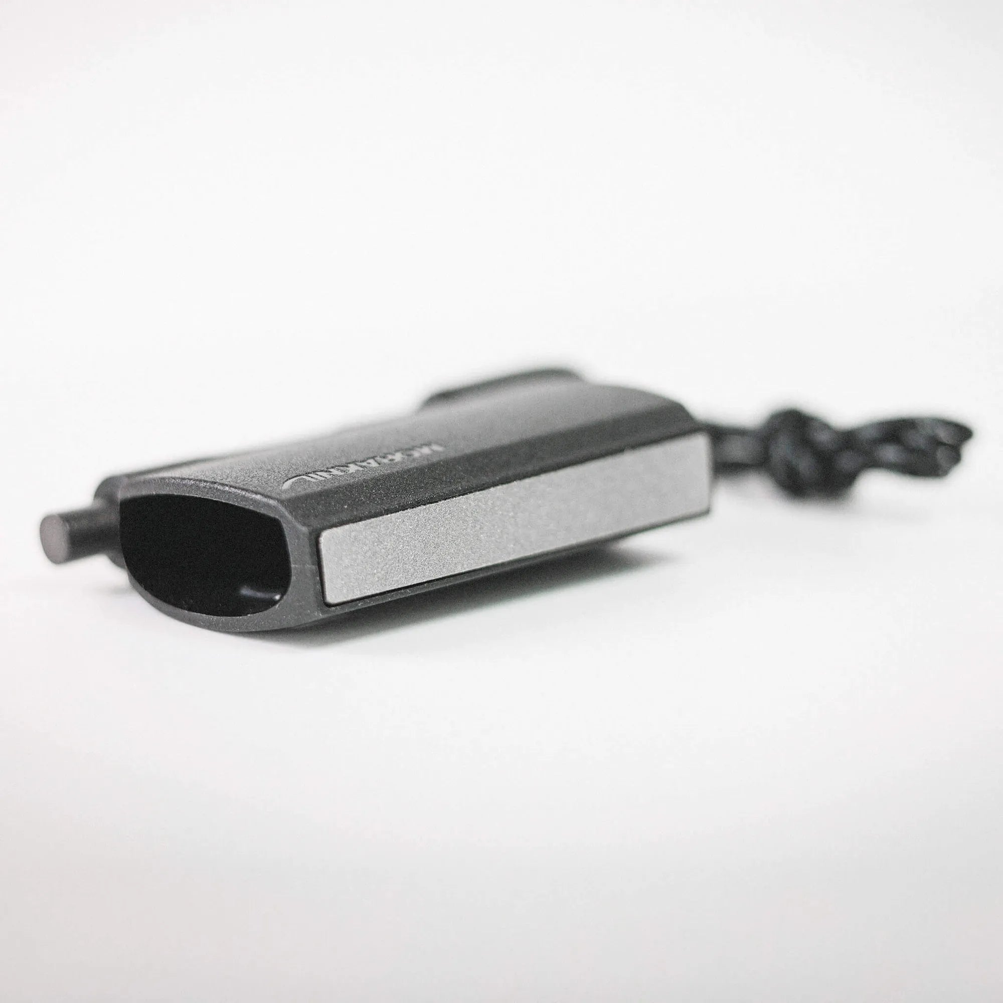 Close-up of a black rectangular electronic device with rounded edges resting on a white surface.