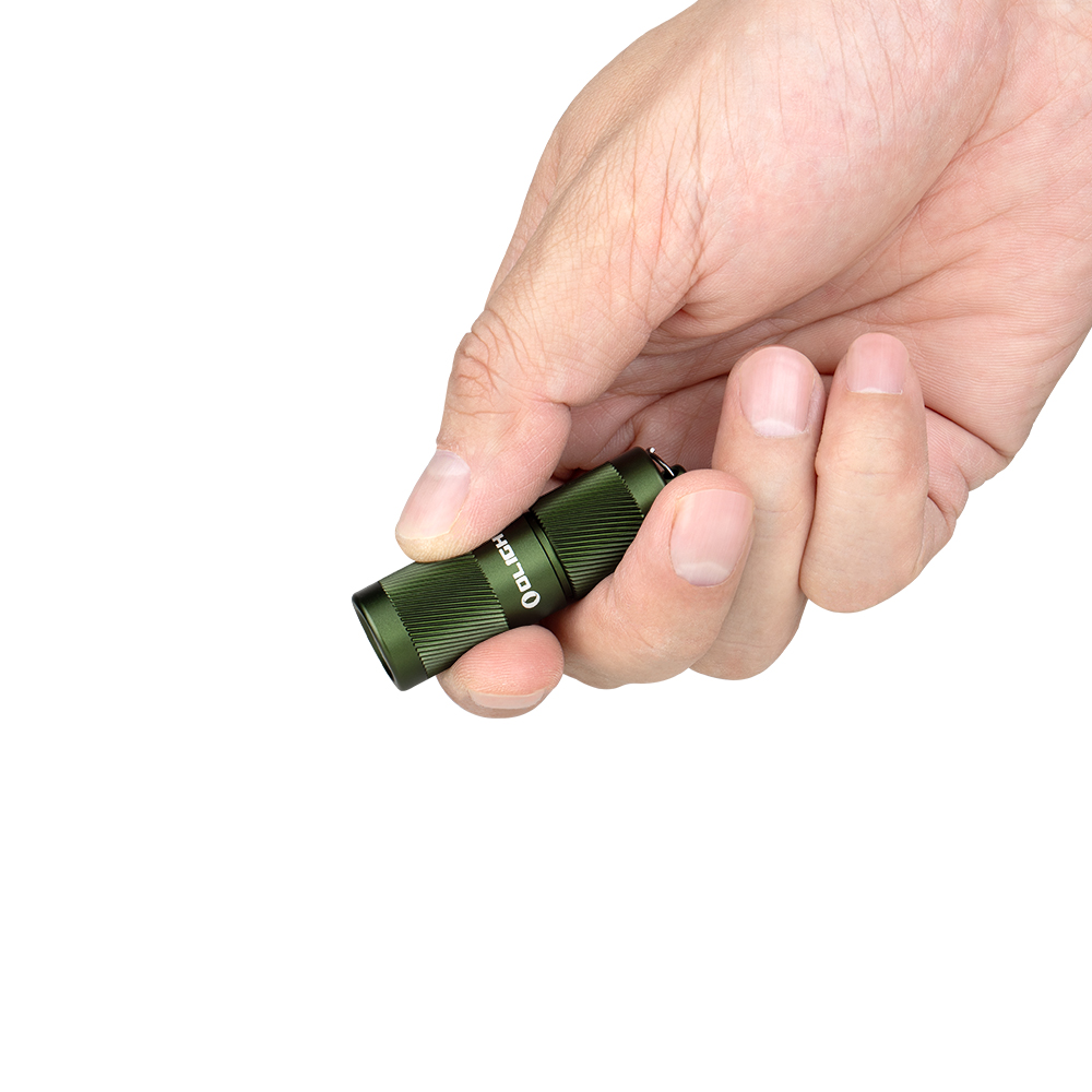 Small green compact flashlight gripped between fingers in a hand, ready to use
